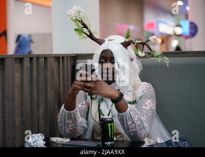 A cosplayer checking her mobile phone during MCM Comic Con at the ExCel London in east London. Picture date: Sunday May 29, 2022. Stock Photo