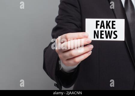 Fake News concept. Human hand with a banner on grey background Stock Photo