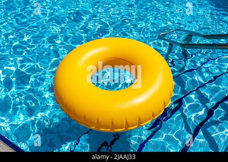 Yellow ring floating in blue swimming pool. Inflatable ring, rest concept Stock Photo