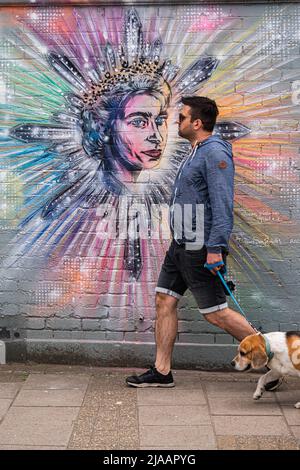 London UK, 29 May 2022. A  man walks his dog past a  mural in Wimbledon by artist Paul Don Smith dedicated to Queen Elizabeth II platinum jubilee . Credit. amer ghazzal/Alamy Live News Stock Photo