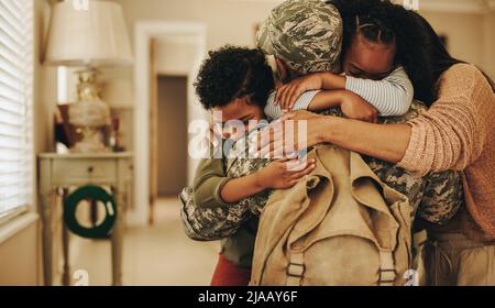 Emotional military homecoming. Patriotic soldier reuniting with his wife and children after serving in the army. Serviceman embracing his family after Stock Photo