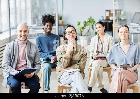 Diverse group of people in audience smiling while attending educational seminar in office, copy space Stock Photo