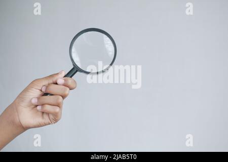 hand holding magnifying glass against white  Stock Photo