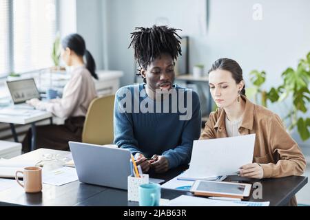 Portrait of two young business people using laptop during educational seminar in office Stock Photo