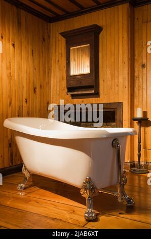 White freestanding roll top bathtub in bathroom inside old 1826 Canadiana cottage style fieldstone home. Stock Photo