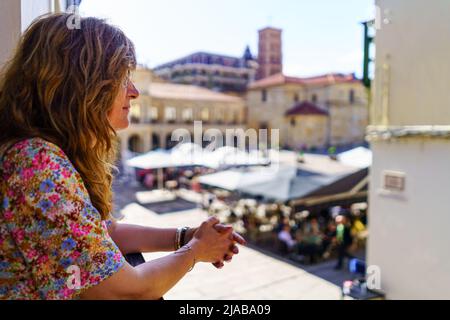 Mature white woman looking out onto the balcony and looking at the medieval city before her eyes. Stock Photo