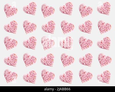 Heart shape made with pink natural spring flowers. Love or Mother's day minimal concept. Valentines day or 8 March idea. Floral seamless pattern. Stock Photo