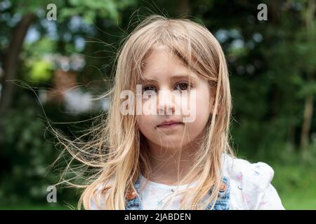 5 Year old girl plays in park while holding her teddy bear Stock Photo