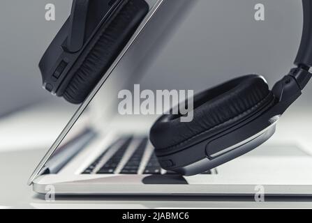 Modern Laptop Computer and Professional Wireless Headphones Digital Audio Mixing Concept. Working with Audio Files. Music Industry. Stock Photo