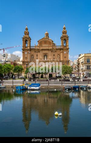 Msida, Malta - May 29th 2022: The Parish church of Saint Joseph which was consecrated on 1894 reflected onto the surface of Msida Creek. Stock Photo