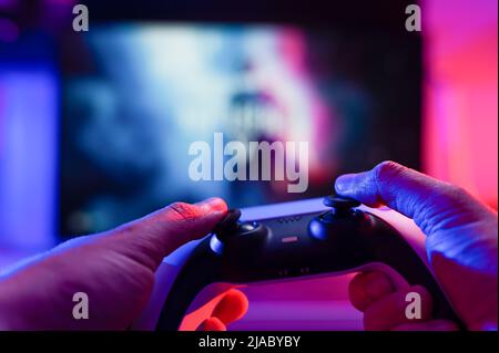 Close-up. The gamer holds a gamepad in his hands. Plays video