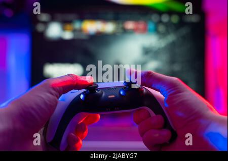 Close-up. The gamer holds a gamepad in his hands. Plays video