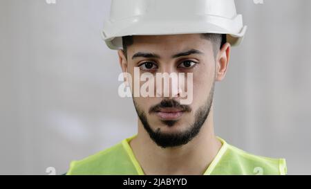 Close-up portrait of serious arabian man male foreman professional inspector builder mechanic engineer wear uniform safety helmet posing at camera Stock Photo