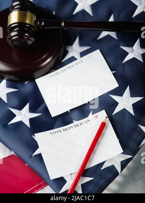 Two ballot papers - vote democrat, vote republican, judicial wooden gavel and red pencil on american flag background. Symbols of fair elections in Ame Stock Photo