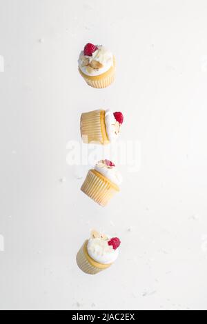 Muffins with cream and fresh raspberries in frozen flight on a white background. Minimalism. There are no people in the photo. There is free space to Stock Photo
