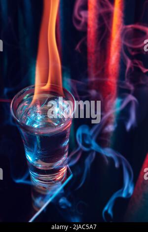Glass of Mexican tequila, vodka with burning liquid. Glass of vodka on black with flames. Stock Photo