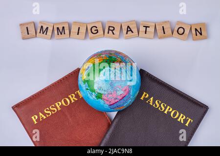 Passports, globe and wooden cubes with text immigration close up. Flat lay style. Stock Photo