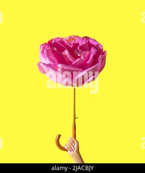 Woman holding umbrella made of pink rose flower on illuminating background. Minimal summer concept. Yellow background. Stock Photo