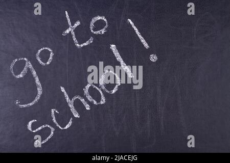 Handwritten inscription go to school on black chalkboard close up. Time for education concept. Stock Photo