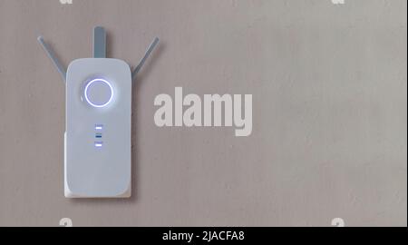 Wifi Extender Wireless repeater home device at power outlet on grey empty wall background. Network booster, router antenna close up view. Copy space. Stock Photo