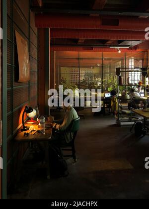 Focused programmer work using laptop sitting at office desk table in cozy dark coworking workspace Stock Photo