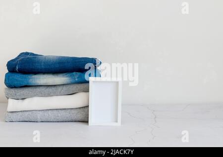 Stack of sweaters  and  blue jeans on grey background, ironing, laundry, home comfort, textile, knitted, women's clothing, cotton, women's casual all- Stock Photo