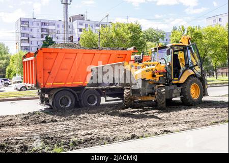 Samara, Russia - May 26, 2022: Dump truck Kamaz and front loader are working on the improvement of city streets in summer Stock Photo