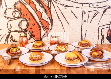 Set of assorted hamburgers with melted cheese, brioche bread on a varnished wooden table Stock Photo