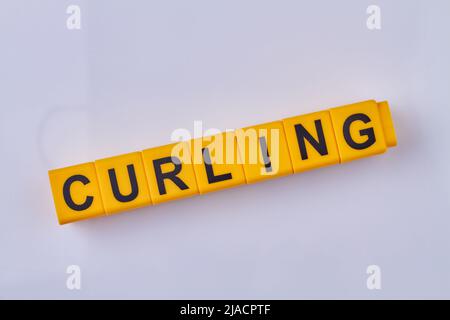 The word curling written on yellow cubes isolated on white background. Type of winter sports game. Stock Photo