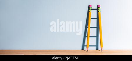 Two Pencils On Desk Casting Shadow Of Ladder - Success Through Education Concept Stock Photo