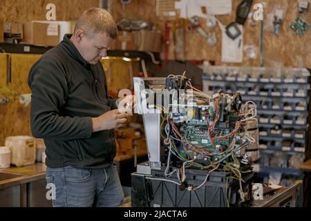 Male electrician repairing coffee machine in workshop Stock Photo