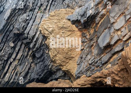 Black and red layers of fragmented rock in geological formation on the Sintra coastline near Cascais Portugal Stock Photo
