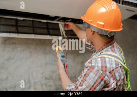 Technician installing an air conditioning unit on a wall, Thailand Stock Photo