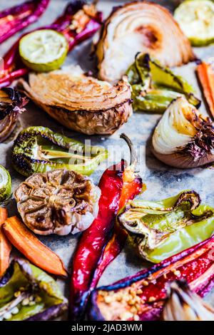 Close-up of roasted red peppers, bell peppers, garlic, onion and carrots on a baking tray Stock Photo