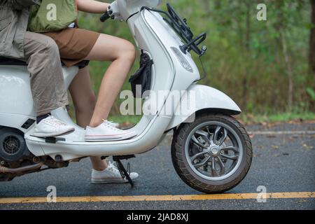 Close-up side view of a couple sitting on a scooter Stock Photo