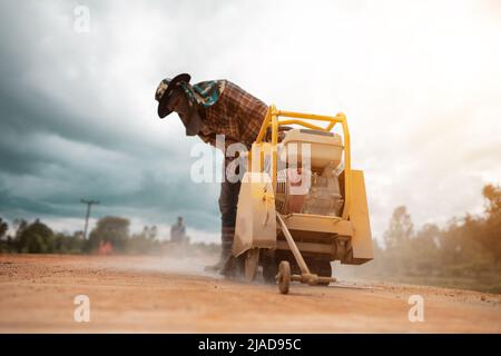 Construction worker using road cutting machinery to cut road surface ...