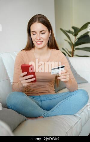 Young woman using phone and on credit card to make easy secure payment online Stock Photo