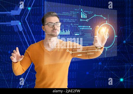 Male programmer using virtual screen on blue background Stock Photo