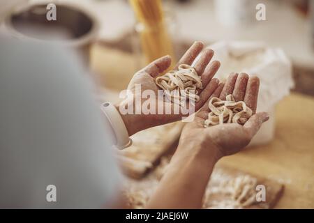 Two palms side by side hold noodles just made from the dough Stock Photo
