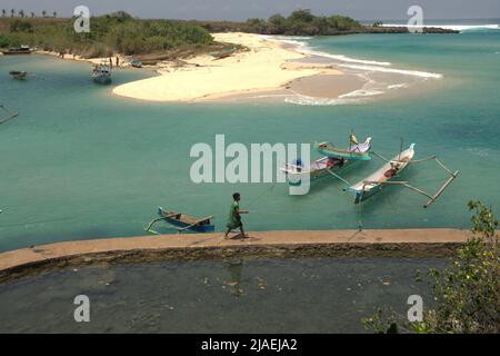 A fisherman walking on a concrete pathway on the fishing beach of Pero in Pero Batang villlage, Kodi, Southwest Sumba, East Nusa Tenggara, Indonesia. Stock Photo