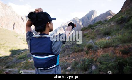 Rear view of sportswoman looking for a path and pointing to the mountain Stock Photo