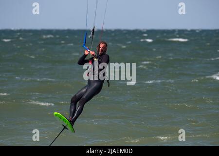 Male Kite Foil Surfer with beard and long hair on the sea Stock Photo