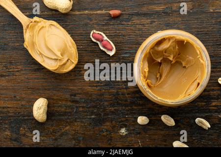 https://l450v.alamy.com/450v/2jaemjg/wooden-spoon-with-a-jar-of-peanut-butter-and-a-bunch-of-scattered-nuts-on-a-vintage-background-2jaemjg.jpg