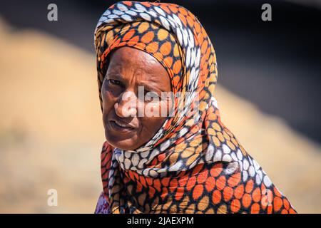 Old Local Woman in Colorful Scarf on the road to Massawa Stock Photo