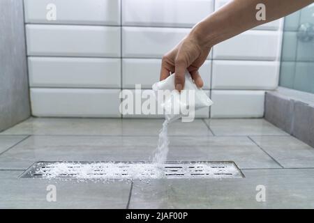 Closeup of female hand pouring pipe cleaner granules. Clean the blockages in bathroom with chemicals Stock Photo