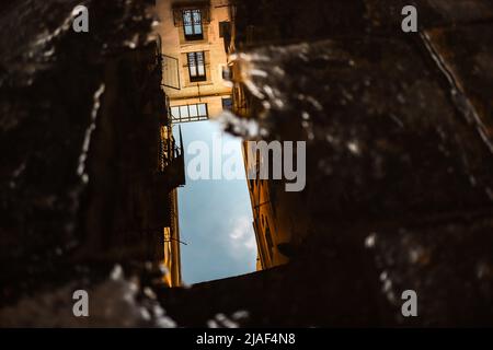 Puddle Reflection of Building with Blue Sky in Spain. Water Puddle on Stone with Architecture. Stock Photo