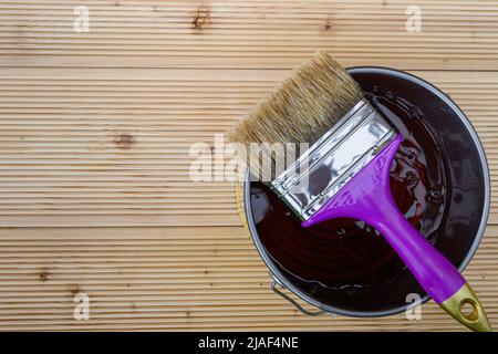Painting new wooden boards for patio by special protective oil. A jar of protective waterproof oil with brush for covering larch floors from bad weath Stock Photo