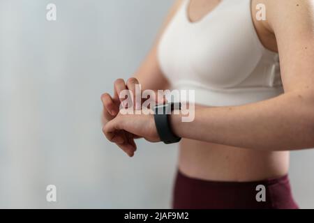 Close up shot of young woman setting and looking at sports smartwatch. Fitness female checking her performance. Stock Photo