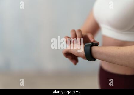 Close up shot of young woman setting and looking at sports smartwatch. Fitness female checking her performance. Stock Photo