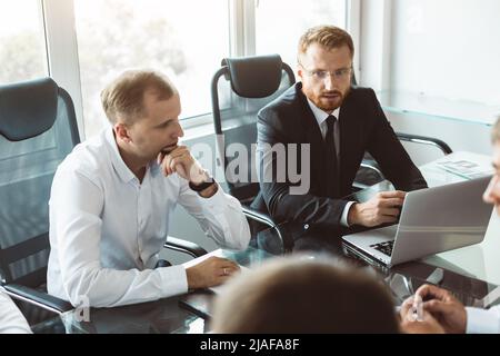 The head of the company sits at the negotiating table and interacts with employees at the meeting. Brainstorming and discussion of the work and Stock Photo